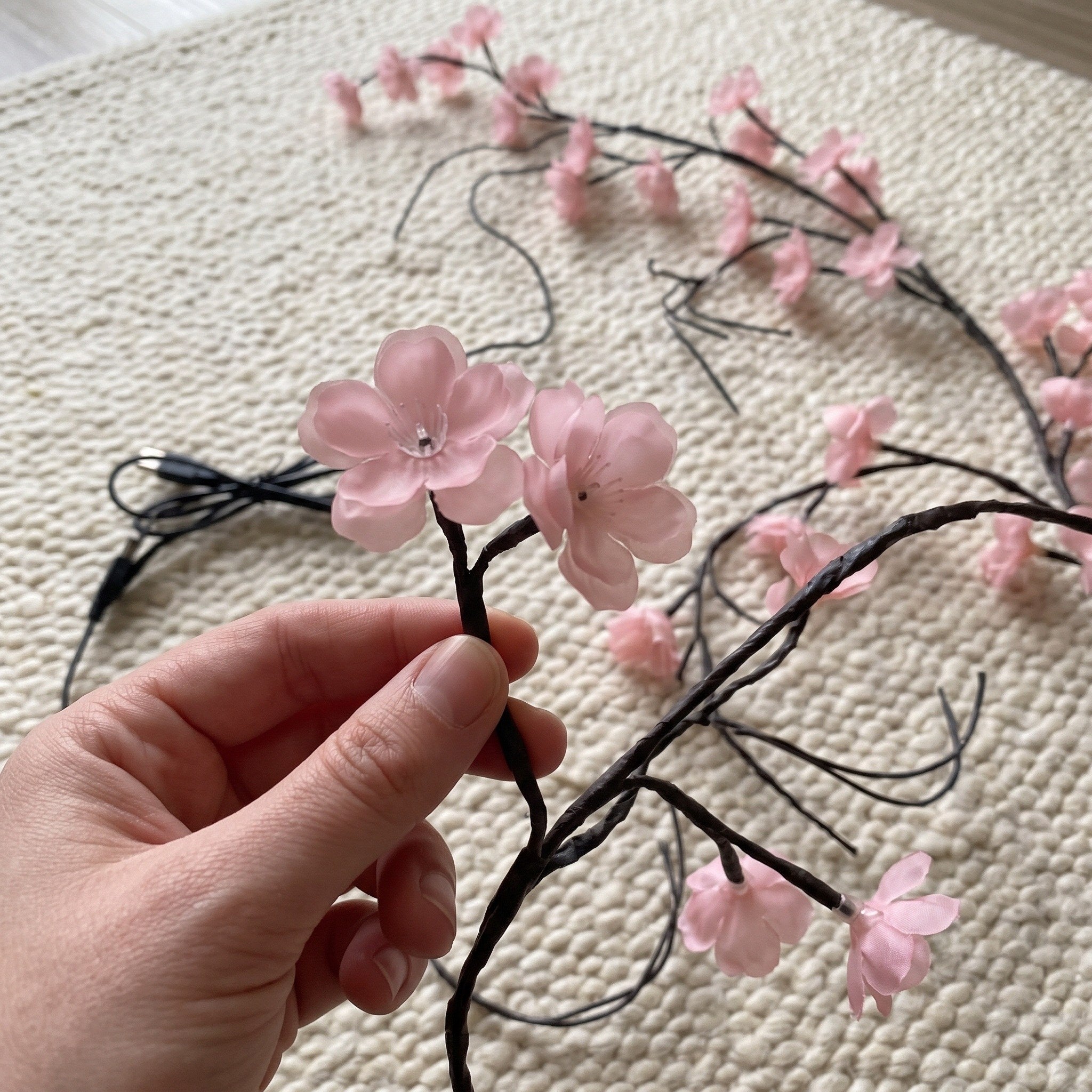 Fingertips beside a pink blossom shade in close view