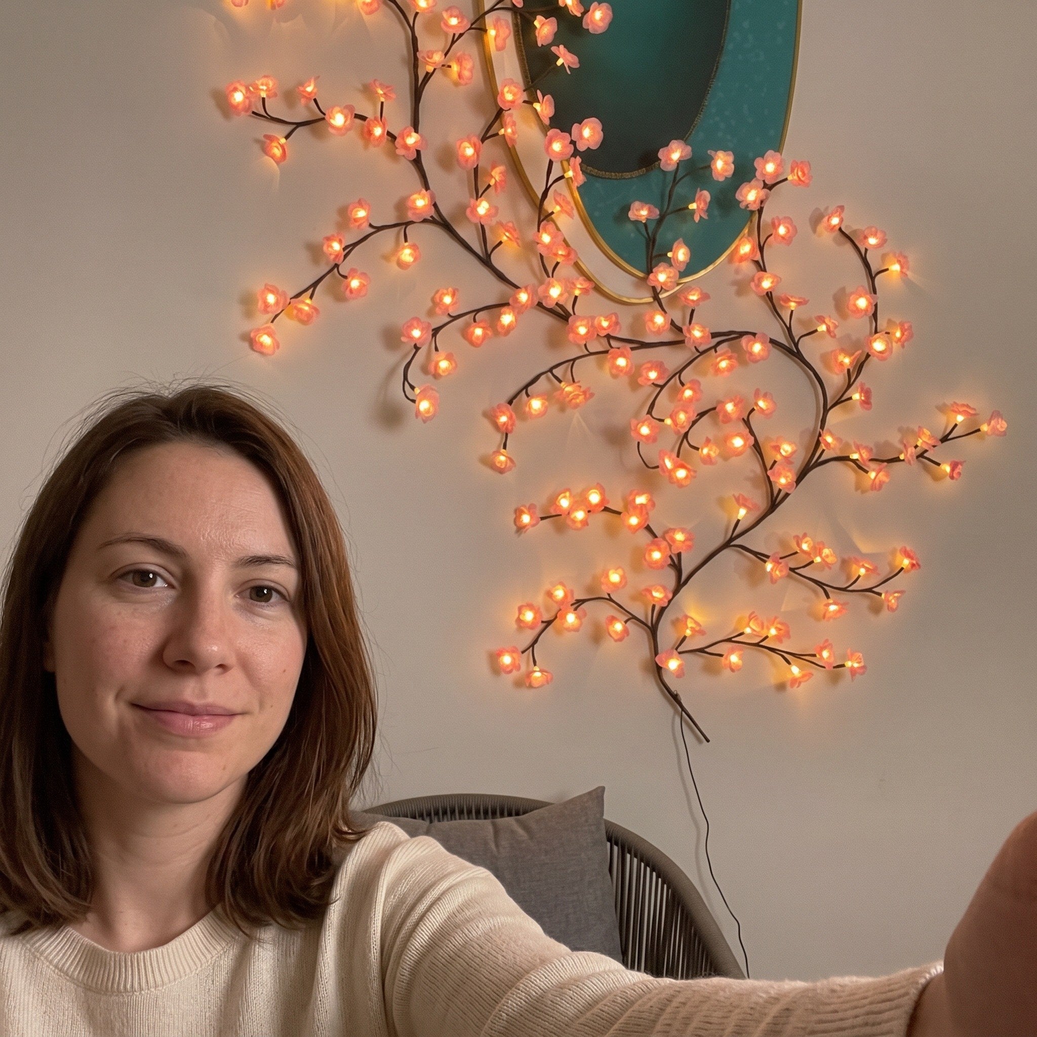 Woman taking a selfie by pink vine lights in a reading corner